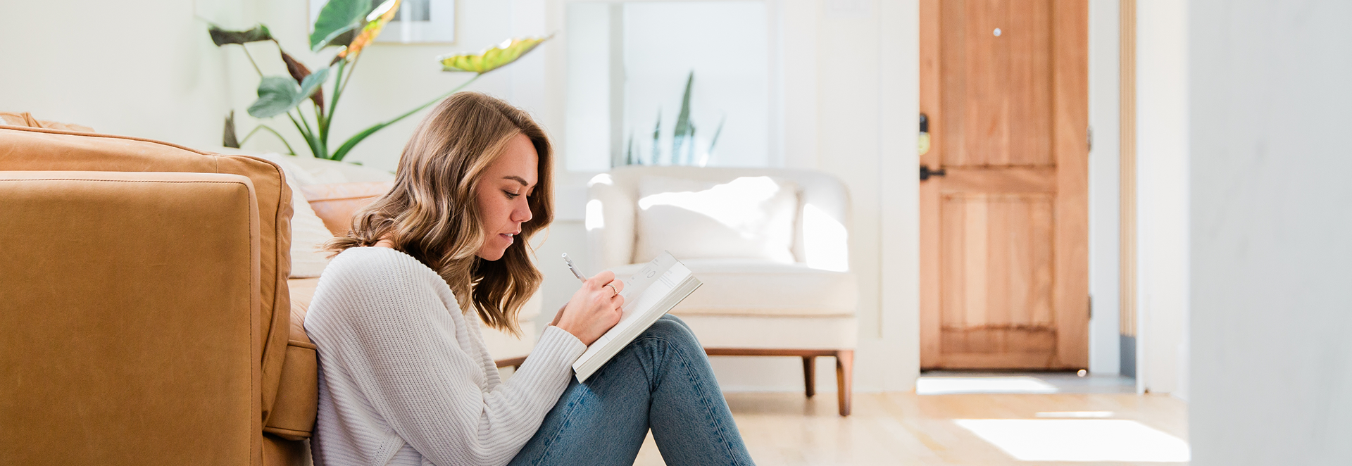 A woman journaling while sitting against a couch